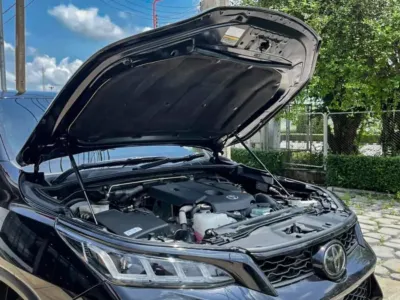 Professional installation of hilux bonnet struts on a black Toyota Hilux for easy engine access.
