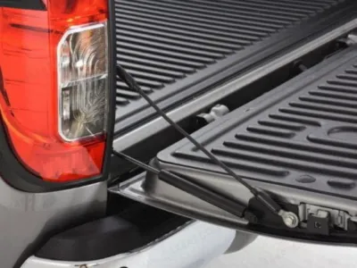 Close-up of an f150 tailgate assist installed on a silver pickup truck.