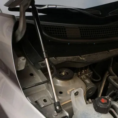 Close-up view of an installed G37 hood strut in the engine bay.