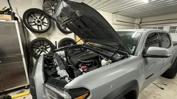 Sokietech hood struts installed on a grey Toyota Tacoma with the hood open in a garage.