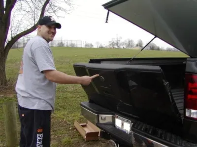 Man pointing to a tailgate assist ford on a black truck.