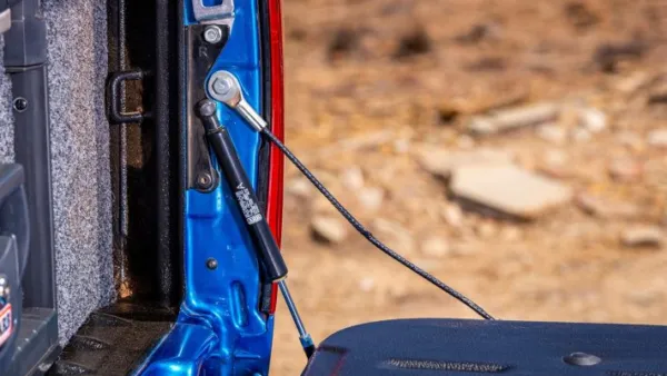Close-up of a tailgate assist ford strut installed on a blue truck.